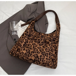 Flat lay of large leopard print hobo bag with brown strap on grey blazer background