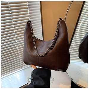 Detail of dark brown crescent shoulder bag with block embossed texture and chain strap