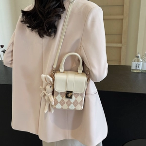 Sac bandoulière chic à motif losanges avec charme lapin et boucle dorée sur un blazer