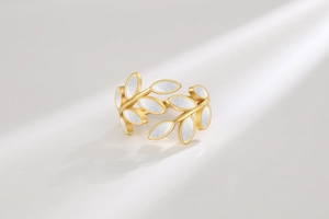 Macro view of gold-plated leaf ring featuring white shell inlay and a layered band
