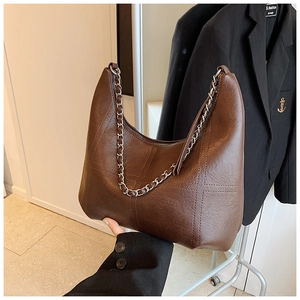 Detail of vintage brown shoulder bag with cross stitching and silver chain strap