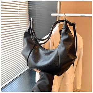 Detail of black pleated shoulder bag with smooth PU leather texture and crescent shape