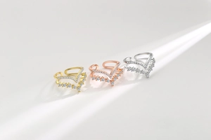 Dettaglio di anelli a V sovrapposti in oro, argento e oro rosa con cristalli pavé lucidi