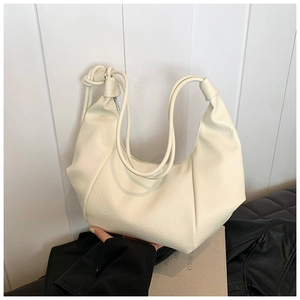Detail view of cream pleated hobo bag showing faux leather texture and knotted strap design