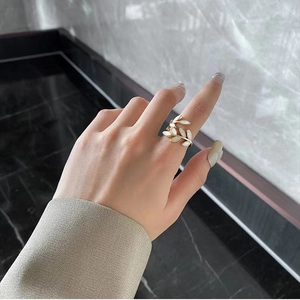Detailed view of adjustable leaf ring in gold finish with white shell inlays on finger