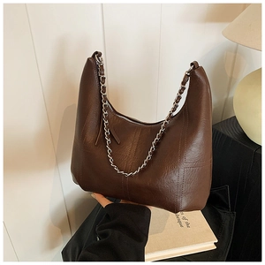 Detail of a dark brown hobo shoulder bag featuring cross stitching and silver metal chain