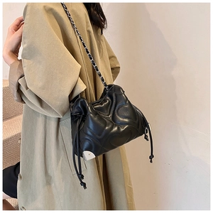 Détail d'un sac seau en cuir matelassé noir avec chaîne argentée et fermeture à cordon