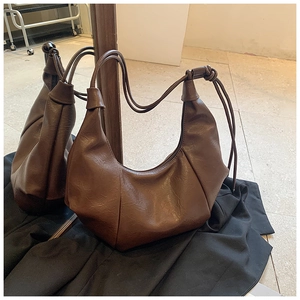 Detail of a brown crescent hobo bag with litchi texture and knotted shoulder strap