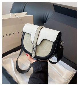 Détail du sac besace bicolore avec fermoir argenté sur un coffret cadeau de luxe
