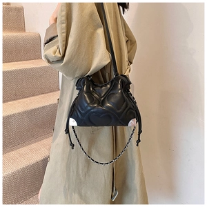 Détail du sac seau noir avec motif matelassé en cœur et coins métalliques argentés