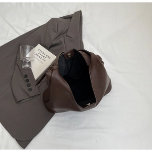 Detail of brown lychee grain leather tote interior with magnetic buckle and inner pocket
