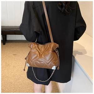 Détail d'un sac seau marron avec matelassage en cœur et coins métalliques sur un mannequin