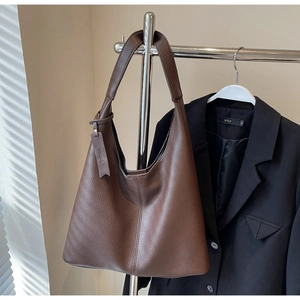 Macro detail of dark brown grainy leather tote bag with vertical stitching and luggage tag