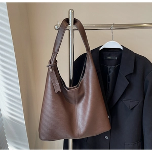 Detail view of large brown lychee grain leather tote bag with elegant side pendant