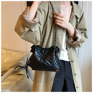 Détail d'un sac à bandoulière matelassé cœur noir avec coins en métal et chaîne