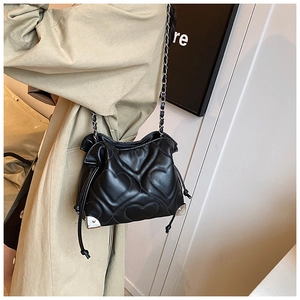 Détail du sac seau noir en cuir matelassé cœur avec coins argentés et bandoulière chaîne