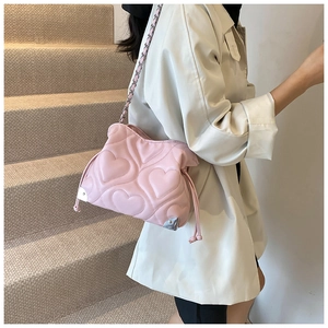Détail du sac à bandoulière rose avec surpiqûres en cœur et coins métalliques argentés