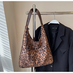 Detailed close-up of leopard print hobo bag with brown leather strap hanging on a hanger