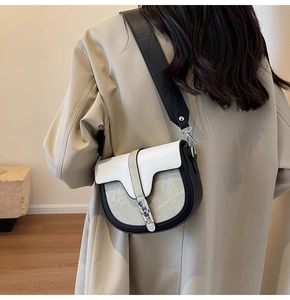 Détail d'un sac selle français avec cuir tricolore et boucle métallique sur bandoulière