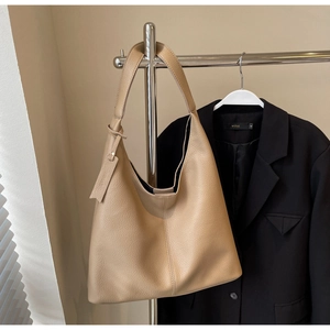 Detailed view of apricot pebbled leather hobo tote bag hanging on a display stand