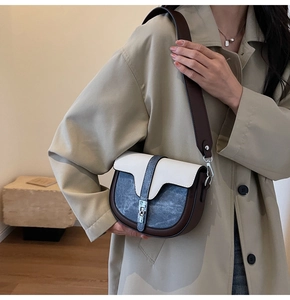 Vue détaillée d'un sac selle color-block avec bandoulière large sur un trench-coat beige