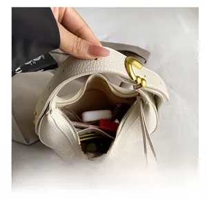 Detail view of white lychee leather saddle bag with heart buckle showing inner capacity