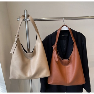 Detail of lychee textured leather large hobo tote bags in gold and caramel colors