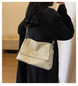 Detail of grey chain shoulder bag with vintage texture worn over a black winter coat