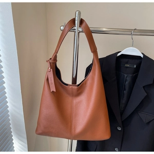 Detail of a brown textured leather hobo bag hanging on a rack with a black blazer