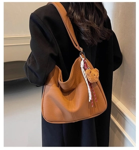 Detail view of brown large tote bag with bear charm and high-quality leather texture