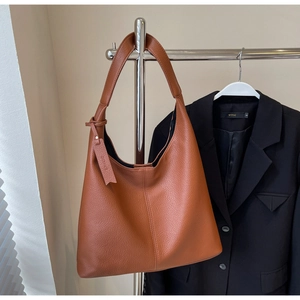 Detailed view of caramel hobo bag with lychee texture hanging on metal rack