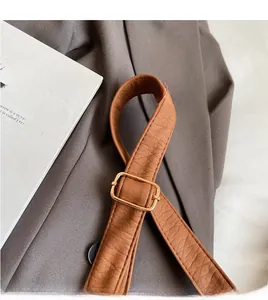 Close-up of adjustable brown litchi pattern leather strap with gold hardware on bag