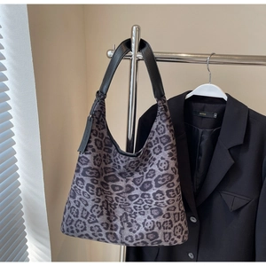 Detail of leopard print tote bag featuring a black leather strap on a chic blazer
