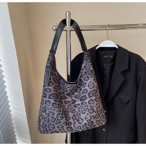Close-up of leopard print tote bag with black leather straps hanging on a metal rack