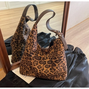 Detailed mirror reflection of a leopard print hobo bag with adjustable leather strap