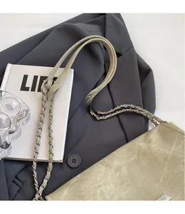 Detail of light khaki suede tote bag with silver chain strap and metal logo on a blazer