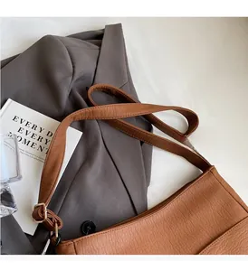 Detail of brown lychee pattern leather shoulder bag with golden hardware and adjustable strap