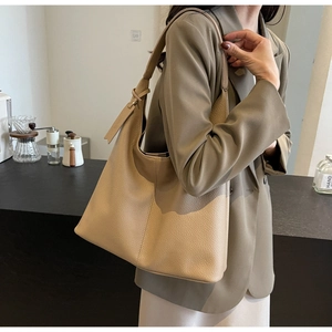 Detail of large beige lychee texture leather tote bag worn as a shoulder bucket bag