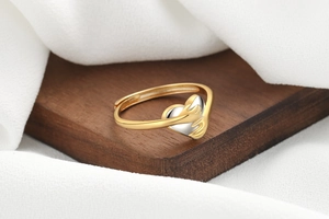 Close-up of a two-tone hugging hands heart ring on a wooden display stand