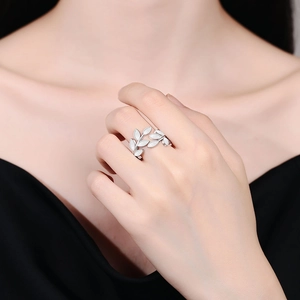 Minimalist silver leaf open ring with white enamel accents worn on a female finger