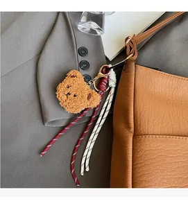 Close-up of a brown plush bear keychain charm attached to a grey suit blazer button