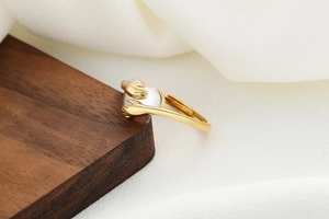 Macro shot of gold-plated hugging hands holding a white round stone on an open ring