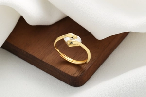 Close-up of golden hugging hands ring with a white heart on dark wood texture background