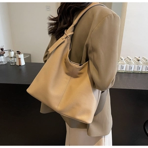 Litchi texture leather tote bag shown from side back view in a minimalist cafe setting