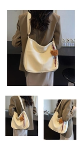 Detail of white hobo bag showing litchi grain texture and bear charm accessory