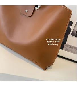 Close-up of brown leather tote bag detail with ORIGINALLY logo and smooth matte texture