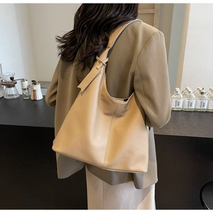 Detailed close-up of a beige crescent tote bag with premium lychee grain leather texture