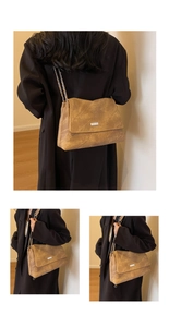 Close-up of vintage brown leather tote bag featuring chain strap and metal logo plaque