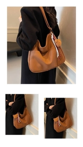 Detail of dark brown leather tote bag with plush bear charm and textured finish