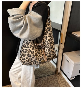 Detail of leopard print tote bag featuring a bow decoration and metal logo plaque